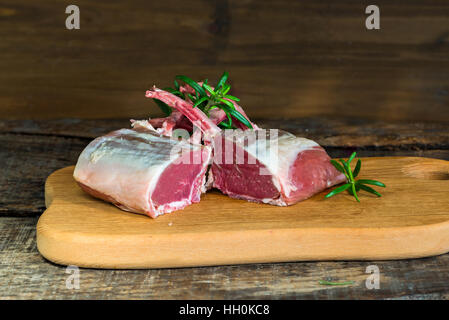 Uncooked rack of lamb with rosemary on wooden background Stock Photo