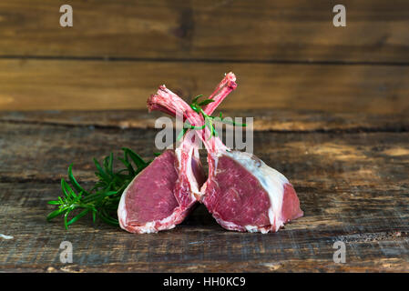Uncooked rack of lamb with rosemary on wooden background Stock Photo