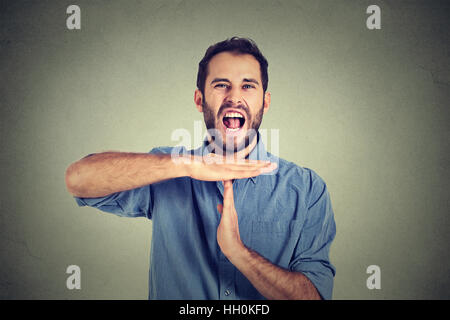 man showing time out hand gesture, frustrated screaming to stop isolated on wall background. Too many things to do overwhelmed Stock Photo