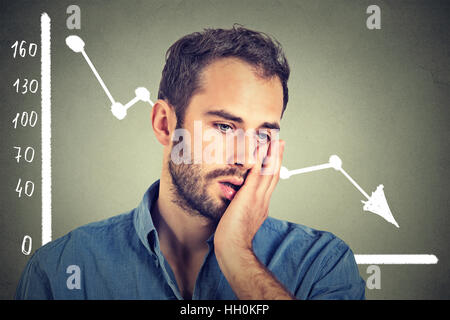 frustrated stressed man desperate with financial market chart graphic going down on gray background. Poor economy financial Stock Photo