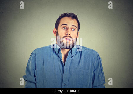 young man shrugging shoulders who cares so what I don't know gesture isolated on gray wall background. Body language express Stock Photo