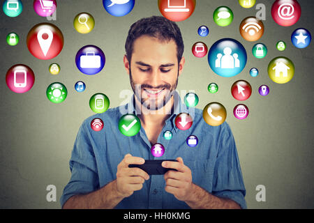 communication technology mobile phone high tech. Happy man using texting on smartphone social media application icons flying out Stock Photo