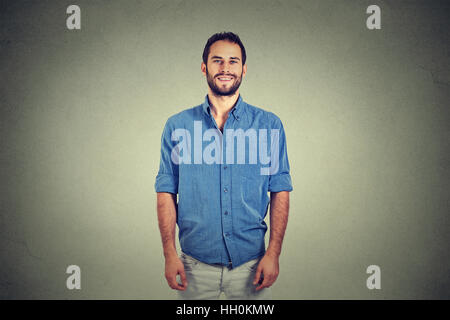 Portrait of a handsome young man smiling isolated against gray wall background Stock Photo