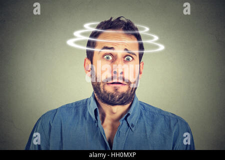 Head is spinning. Surprise astonished man. Closeup portrait man looking surprised in full disbelief wide open mouth isolated grey wall background. Hum Stock Photo