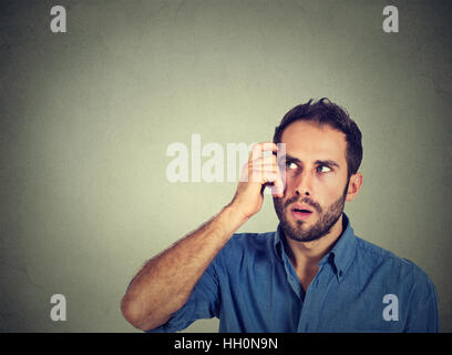 Closeup portrait young man scratching head, thinking deeply about something, looking up, isolated on grey wall background. Human facial expression, em Stock Photo