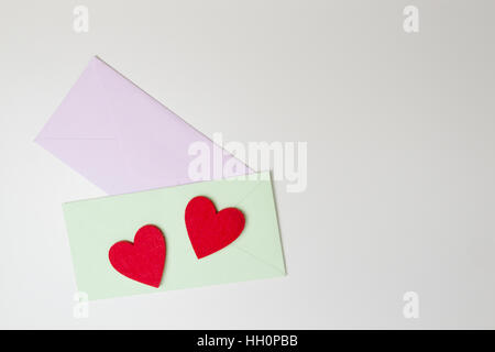 Envelopes and two felt red hearts on white table. Top view. Stock Photo
