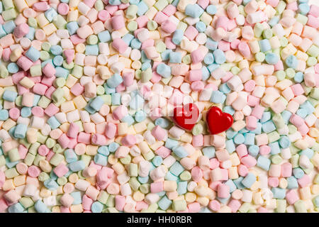 Two red hearts on colorful mini marshmallows background Stock Photo