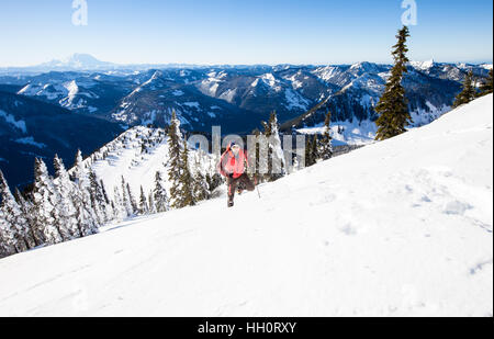 A man snowshoeing up a mountain in the North Cascades Mountains of Washington State Stock Photo