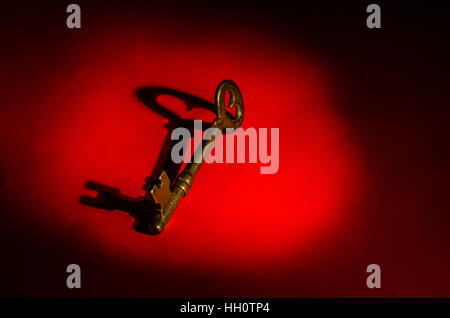A skeleton key on red background with shadows and room for text or copy Stock Photo