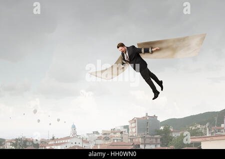 Young businessman with paper wings flying in sky Stock Photo