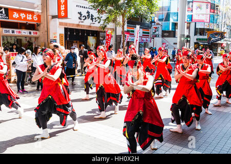 Japanese Yosakoi Dance Festival. Female team of young women performing historical story dance in shopping arcade. Dressed in red robes, arms crossed. Stock Photo