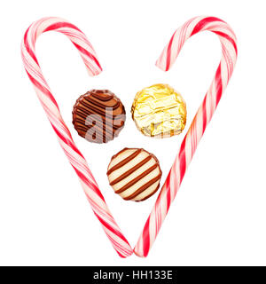 Heart made of candy canes with three chocolate candies inside isolated on white background Stock Photo