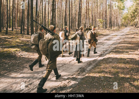 Group of unidentified re-enactors dressed as Soviet russian soldiers goes along forest road. Stock Photo