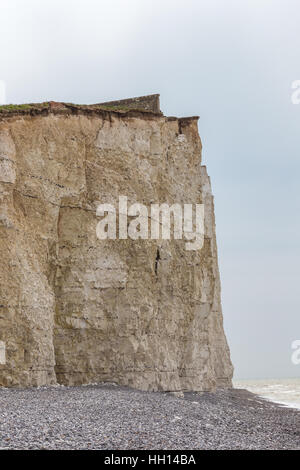 Taken in early summer on a cloudy day of this close up of the chalk cliff face and looking up to evidence of buildings that have fallen into the sea. Stock Photo
