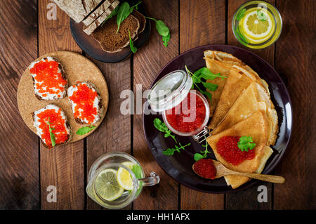 Pancakes with red caviar on plate. Russian cuisine. Maslenitsa. Flat lay. Top view