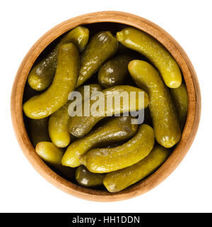 Cornichons, pickled cucumbers in wooden bowl. Green tart French pickles, made from small gherkins. Gherkin, known as pickle. Stock Photo