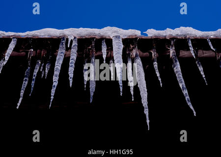 icicles hanging from edge of roof. Stock Photo