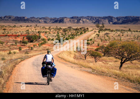 Woman cycling  towards Parc National Isalo in Madagascar Stock Photo