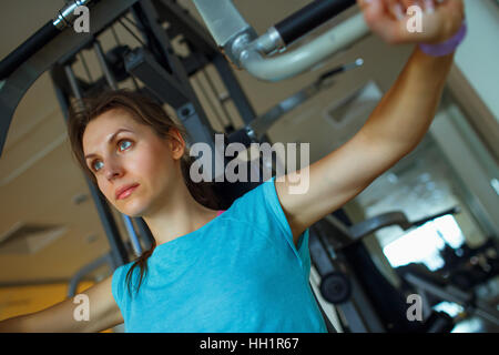 Athletic woman works out on training apparatus in fitness center Stock Photo