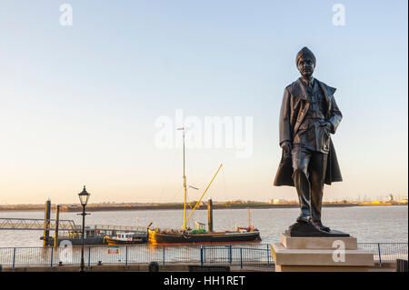 The statue to Mahinder Singh Puiji DFC on the prom at Gravesend Kent. With THames barge moored at pier. Stock Photo