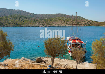 Round the island boat posideon moored on the island of The monastry of Saint emilianos on the west coast of Symi Greece Stock Photo