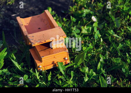 Filtered vintage orange car toy truck on green grass detail Stock Photo