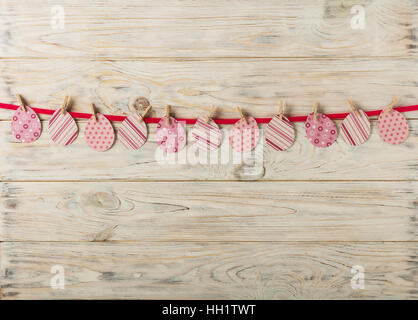 Easter decor. Paper egg with a pink ribbon on a light wooden background. Selective focus. Stock Photo