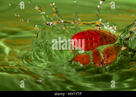 Strawberry dropping on the water in the green plate. Stock Photo