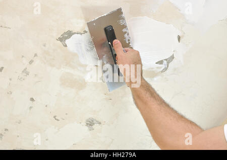 Applying spackle compound with a finishing trowel to a ceiling Stock Photo