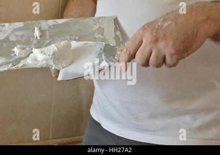 Preparing spackling compound with a finishing trowel and spatula before applying on a wall Stock Photo