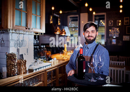 The waiter, sommelier, bartender with  beard carrying a tray  wi Stock Photo