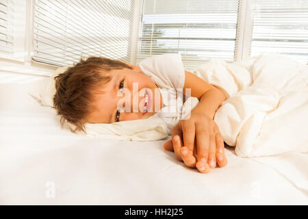 Smiling boy lying in his bed looking at camera Stock Photo