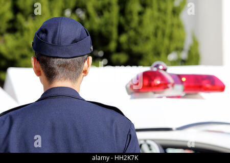 Back view of Japanese police officer with patrol car Stock Photo
