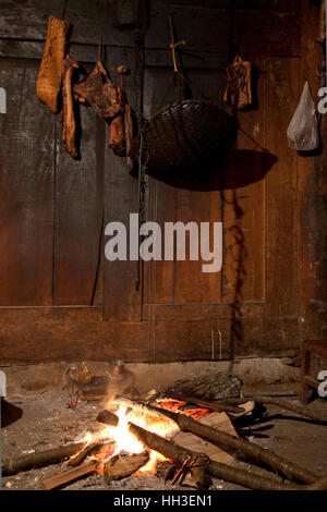 Slabs of meat hung up above a log fire to make smoked meat in the living room of an old farmhouse in a remote village in the mountains of west China. Stock Photo