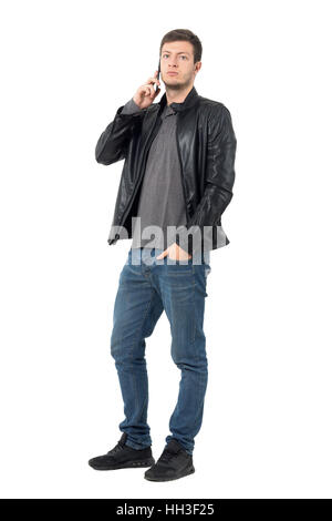 Confident young casual man wearing leather jacket on the phone with hand in pocket. Full body length portrait isolated on white Stock Photo