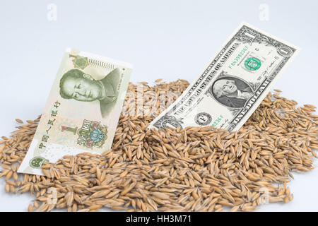 Pile of wheat grain with Chinese 1 Yuan and US  Dollar banknotes / bills - for concept of US-China trade war / tariff war after import duties raised. Stock Photo