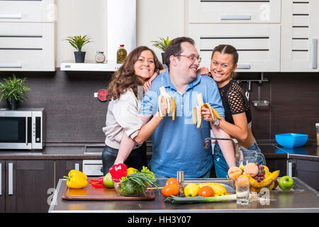 Two young women are fed bananas midle age man Stock Photo