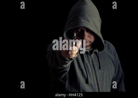 Man in green hoodie points gun Stock Photo