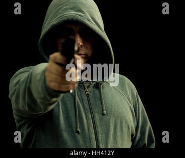 Man in green hoodie points gun Stock Photo