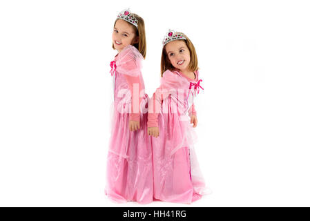 Portrait of Little Twin Girls dressed as princess in pink. Happy children ready for costume party. Cute smiling joyful twins are wearing royalty costu Stock Photo