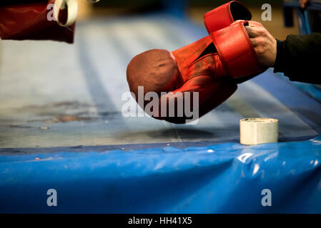 Hand is picking old red boxing glove from the old ring floor Stock Photo