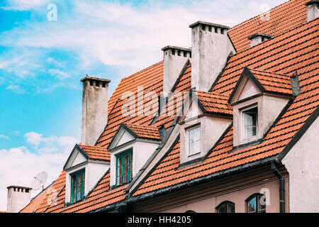 Riga, Latvia. The View Of Mansard Red Tile Roof With Four Gable Fronted Dormer Windows On The Old Building Under Blue Sky. Stock Photo