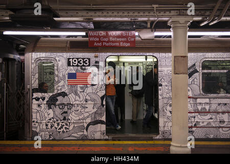 Passengers in a painted subway train during a stop at the waiting platform in a station. New York City, United States of America Stock Photo