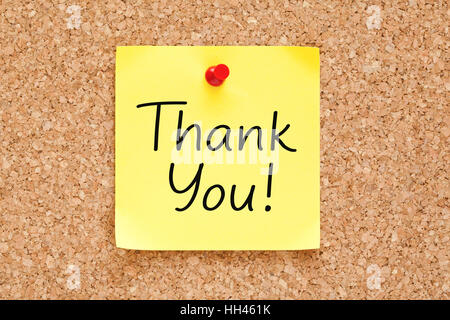 Thank You handwritten on yellow sticky note pinned on bulletin cork board. Stock Photo