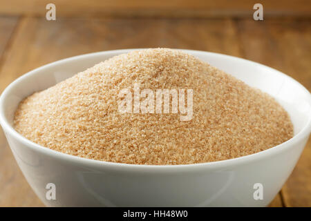Brown sugar in white bowl on wooden table Stock Photo