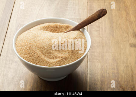 Brown sugar in white bowl on wooden table Stock Photo