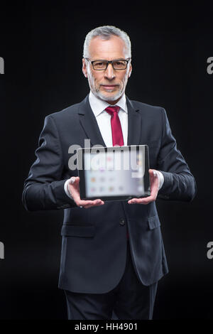 Mature businessman holding digital tablet and smiling at camera Stock Photo