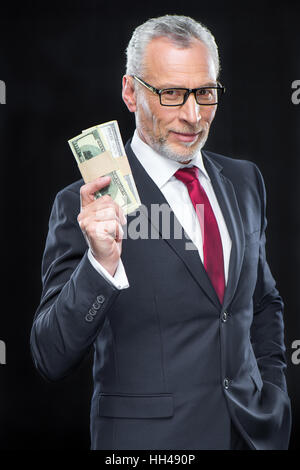 Handsome mature businessman holding dollar banknotes and smiling at camera Stock Photo