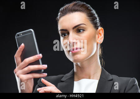 Smiling attractive businesswoman using smartphone on black Stock Photo