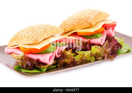 Sandwiches with fresh vegetables, ham and cheese on plate. Stock Photo